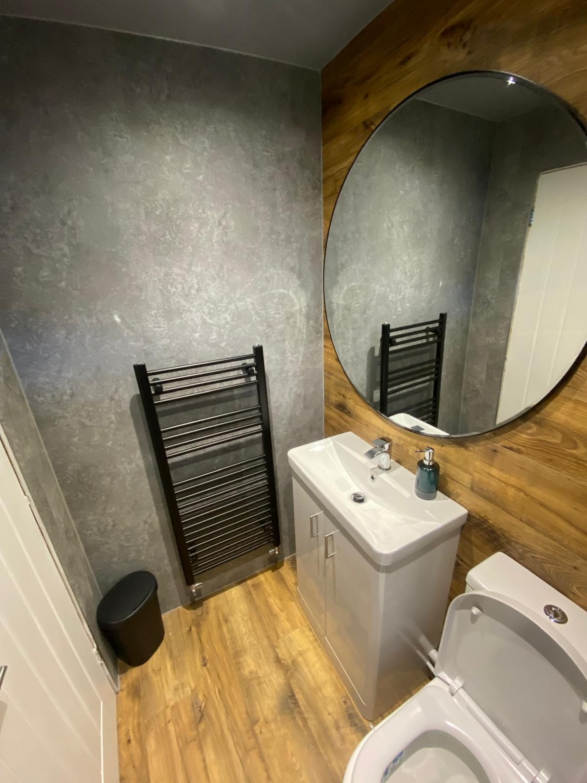 Modern bathroom with round mirror and oak vanity unit